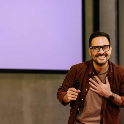 A thankful businessman finishes a presentation, standing in the conference hall, holding a microphone.